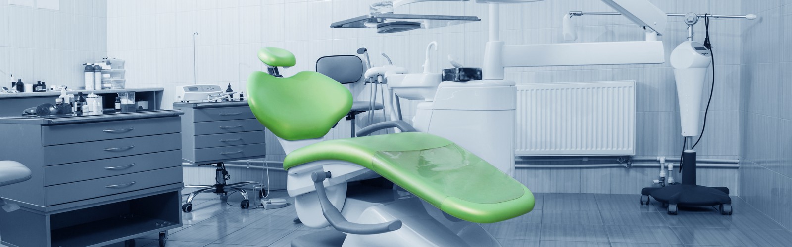 Salle de soins dentaires avec fauteuil vert et équipements de traitement.